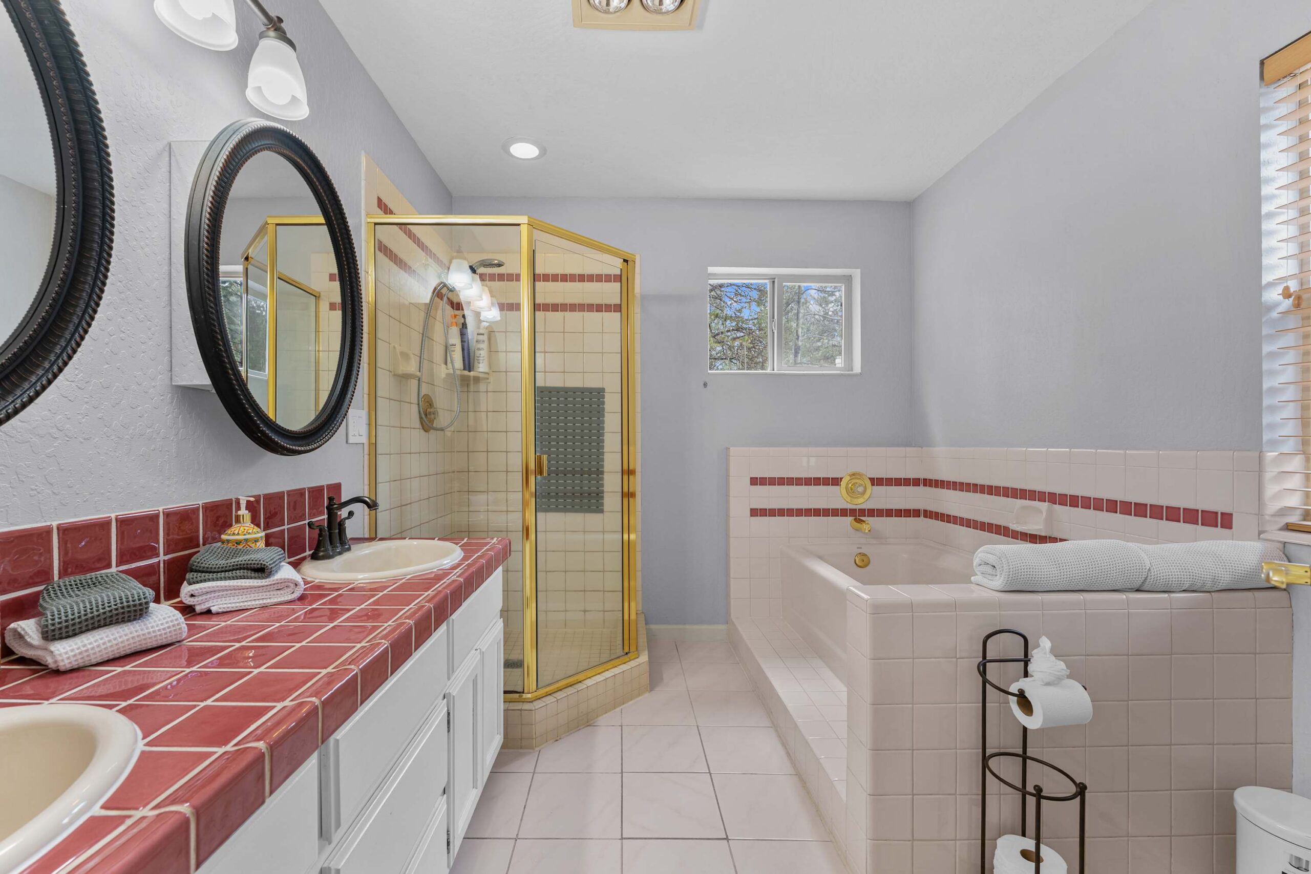 Bathroom with red-tiled counters and gold fixtures in a Truckee vacation rental, featuring a bathtub and shower.