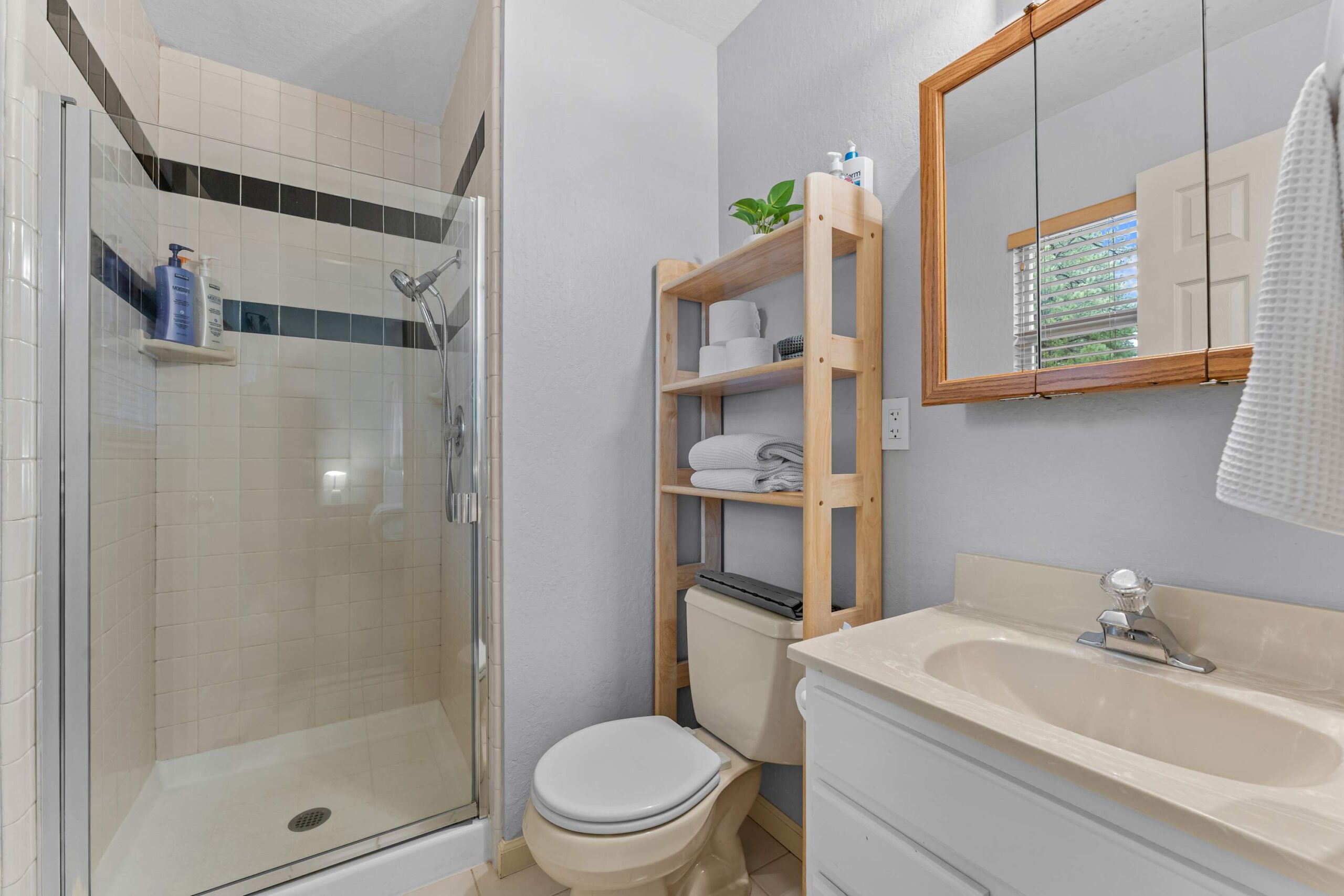 Bathroom in a Truckee vacation rental with a glass shower, wooden shelf, and sink area.