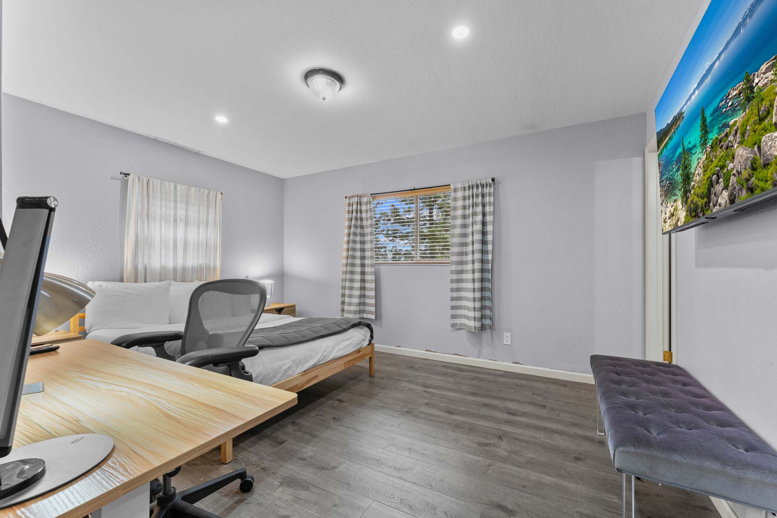 Modern bedroom in a Truckee vacation rental with a bed, desk, office chair, and scenic artwork on the wall.