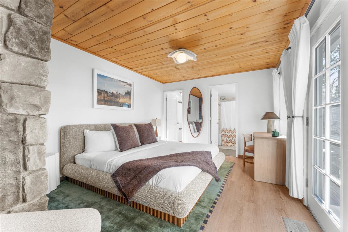 Cozy bedroom in Kings Beach vacation rental, featuring wooden ceiling, stone accent wall, and elegant decor.