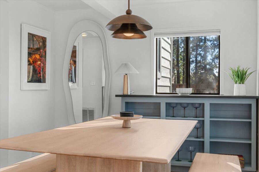 Modern dining area in a Kings Beach vacation rental with minimalist decor, wooden table, and large window.