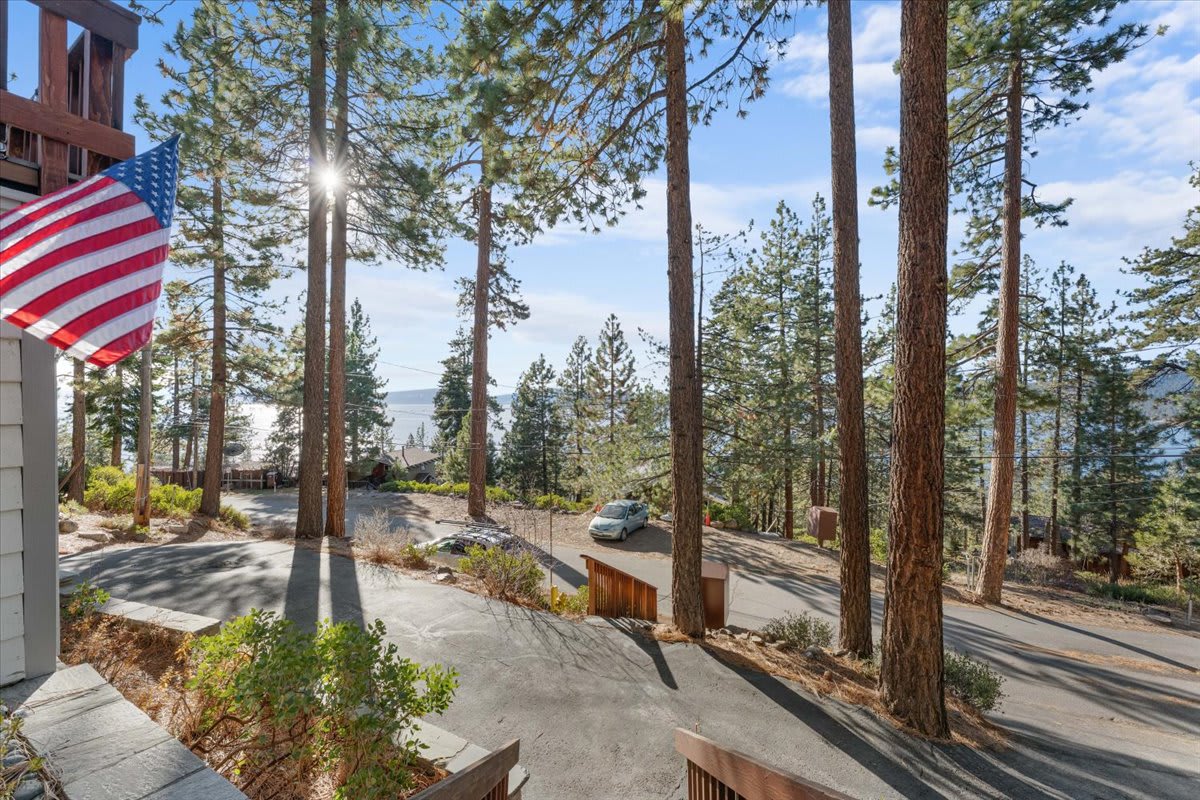 Kings Beach vacation rental view with tall trees, a visible lake, and an American flag on a sunny day.