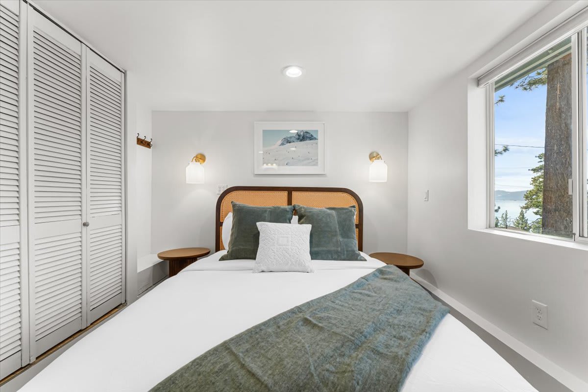 Modern bedroom in Kings Beach vacation rental with large window, cozy bed, and nature views.