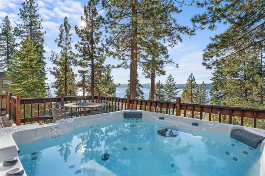 Hot tub on a deck overlooking a lake and trees in Kings Beach vacation rental, offering a serene and relaxing view.