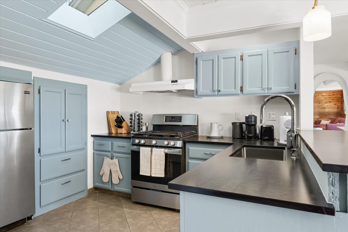 Modern kitchen in Kings Beach vacation rental with blue cabinets, stainless steel appliances, and skylight.