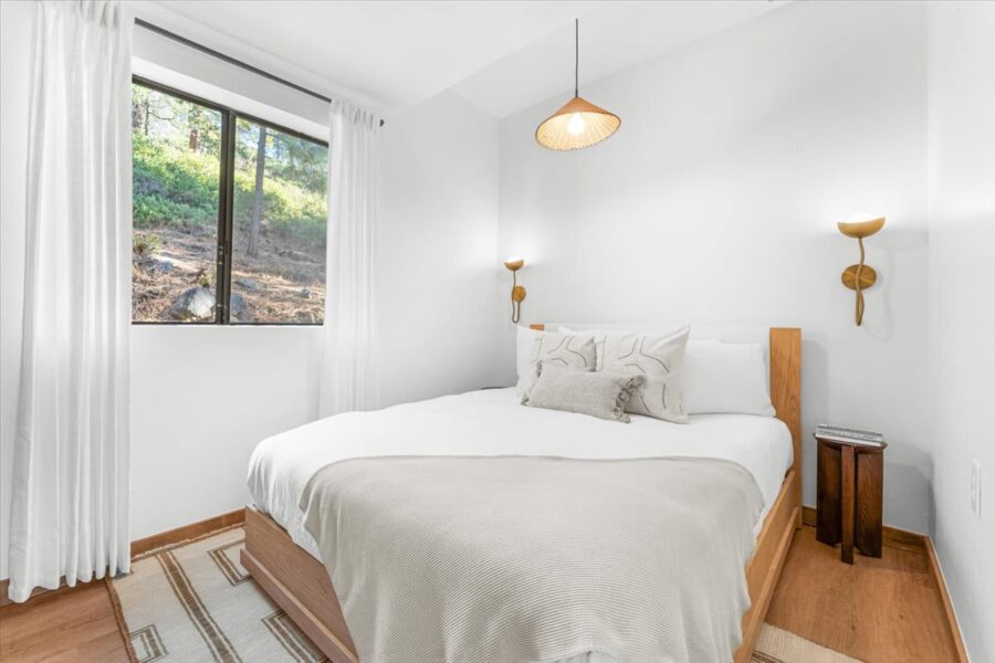 Cozy bedroom in a Kings Beach vacation rental with a large window and minimalist decor.