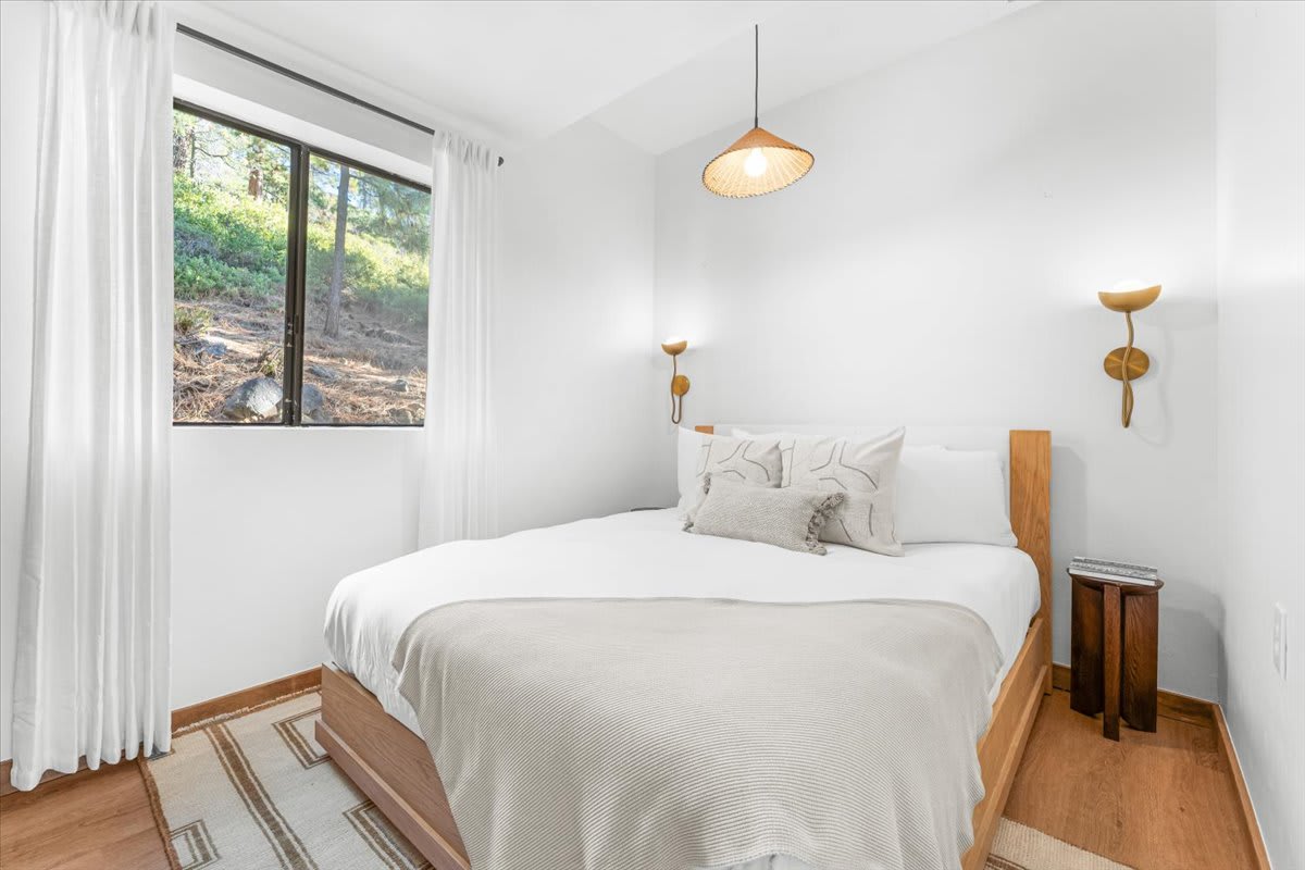 Cozy bedroom in a Kings Beach vacation rental with a large window and minimalist decor.