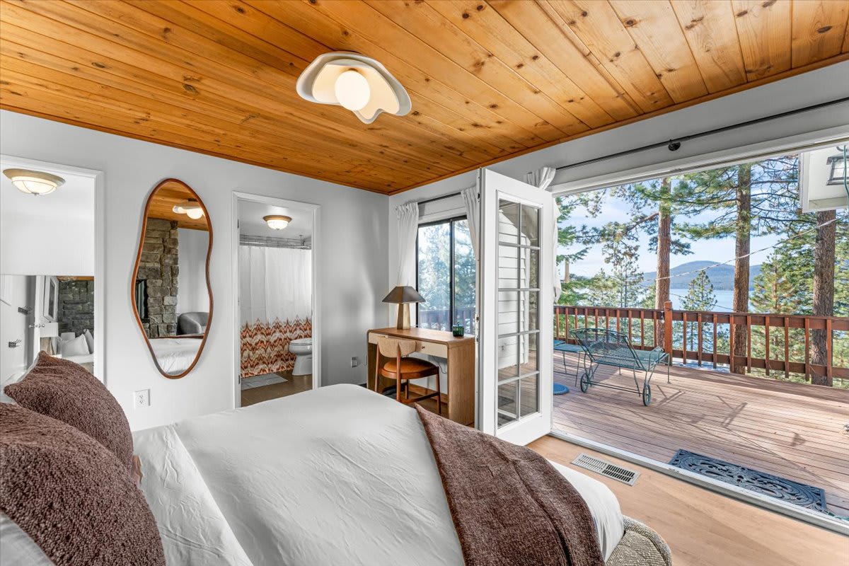 Kings Beach vacation rental bedroom with wood ceiling, deck access, scenic view, and cozy decor.