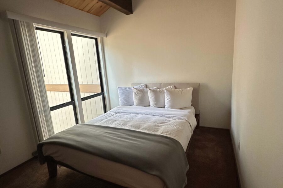 Cozy bedroom in a Kings Beach vacation rental, featuring a neatly made bed and large window with natural light.