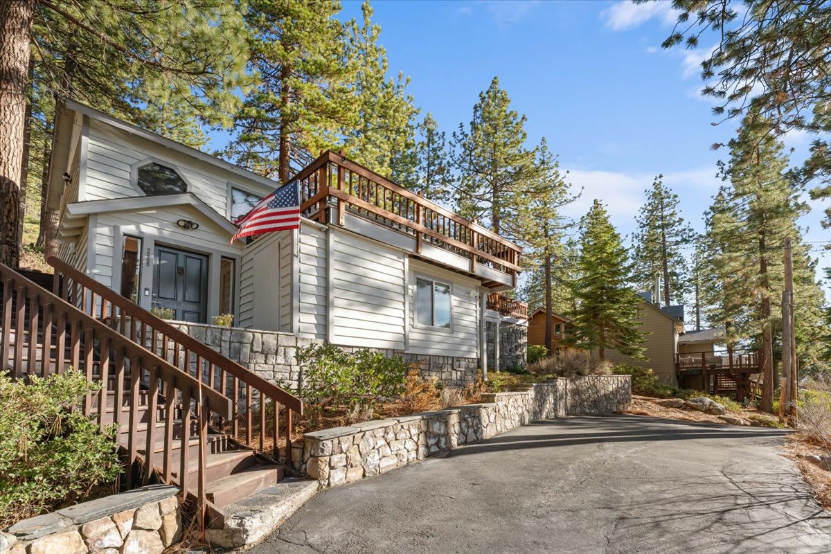 Vacation rental in Kings Beach with a rustic exterior, surrounded by tall pine trees and featuring a wooden deck.