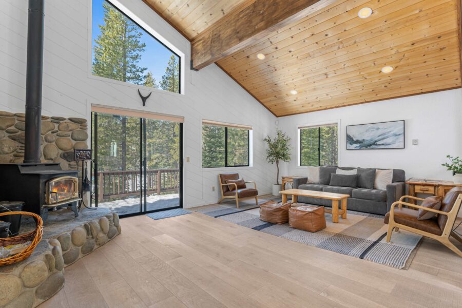 Spacious Truckee vacation rental with wood stove, large windows, and cozy seating area overlooking the forest.