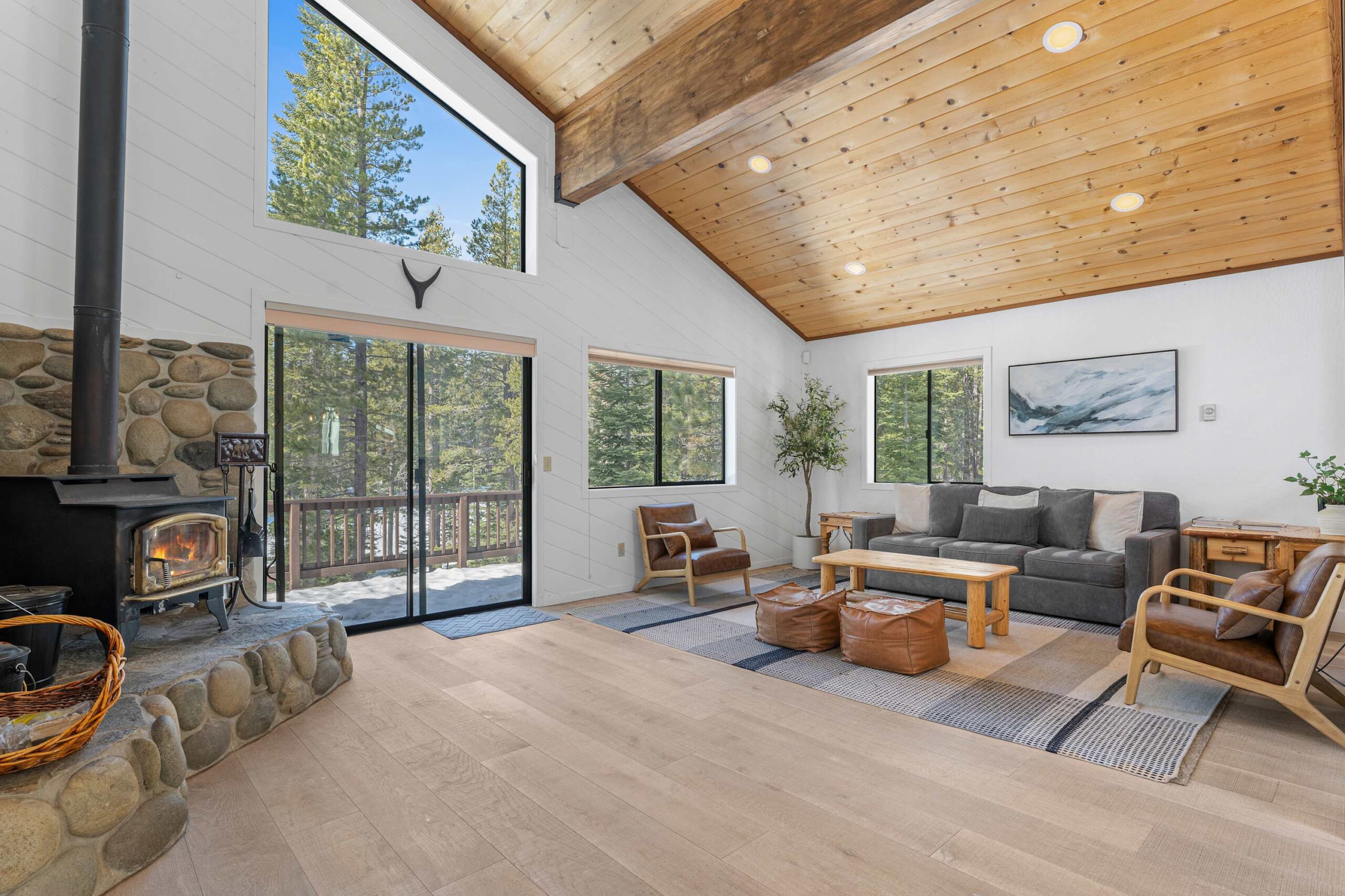 Spacious Truckee vacation rental with wood stove, large windows, and cozy seating area overlooking the forest.