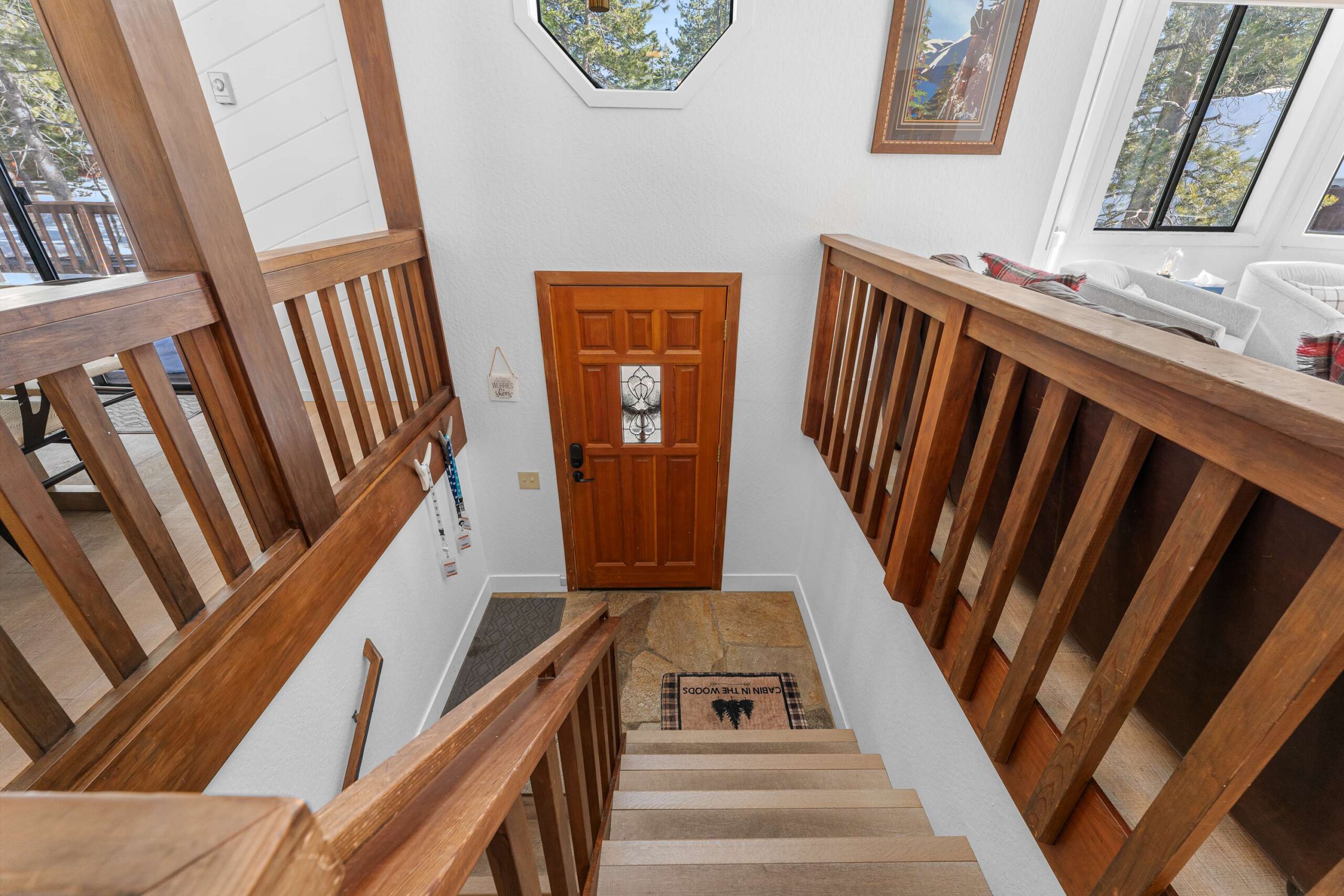 Staircase with wood railings leading to front door in a Truckee vacation rental, featuring bright interior and decor.