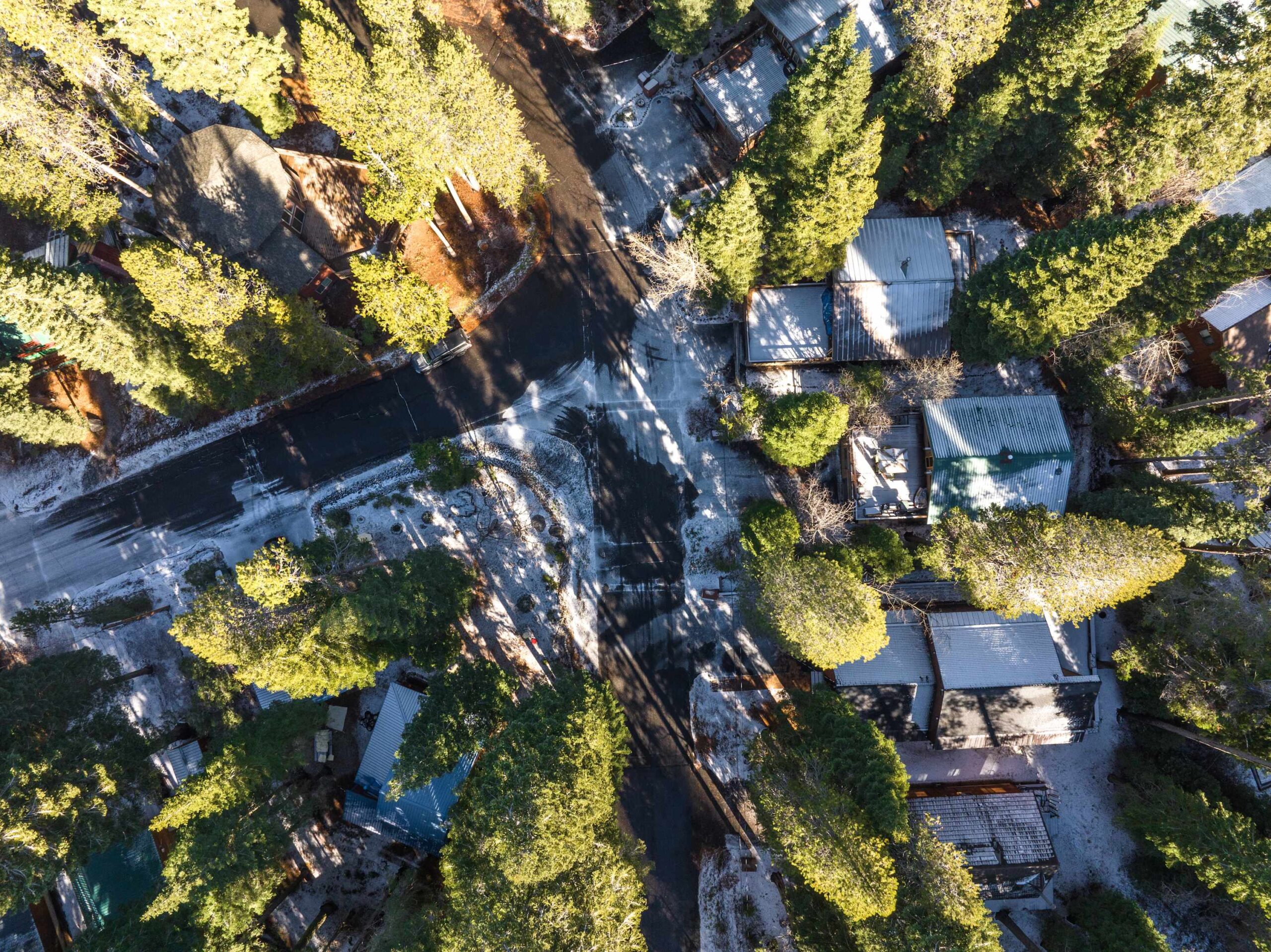 Aerial view of cozy vacation rentals surrounded by snow-dusted trees in Truckee, at a crossroad.