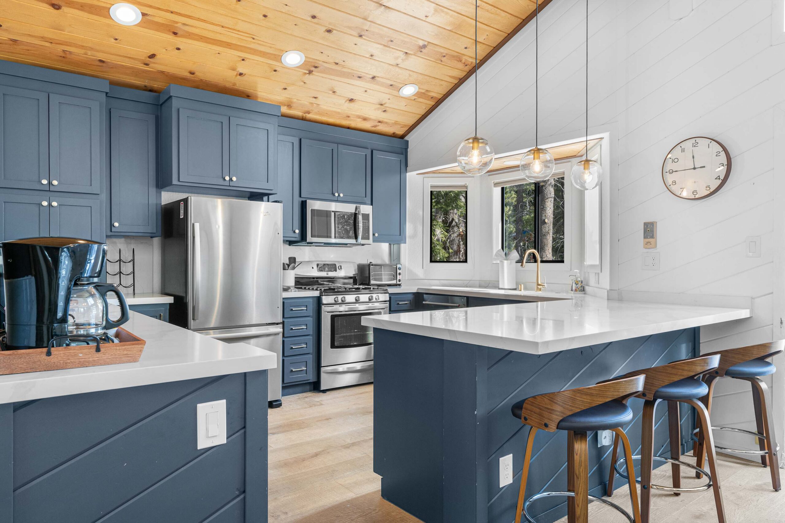 Modern kitchen in Truckee vacation rental with blue cabinets, stainless steel appliances, and large windows.