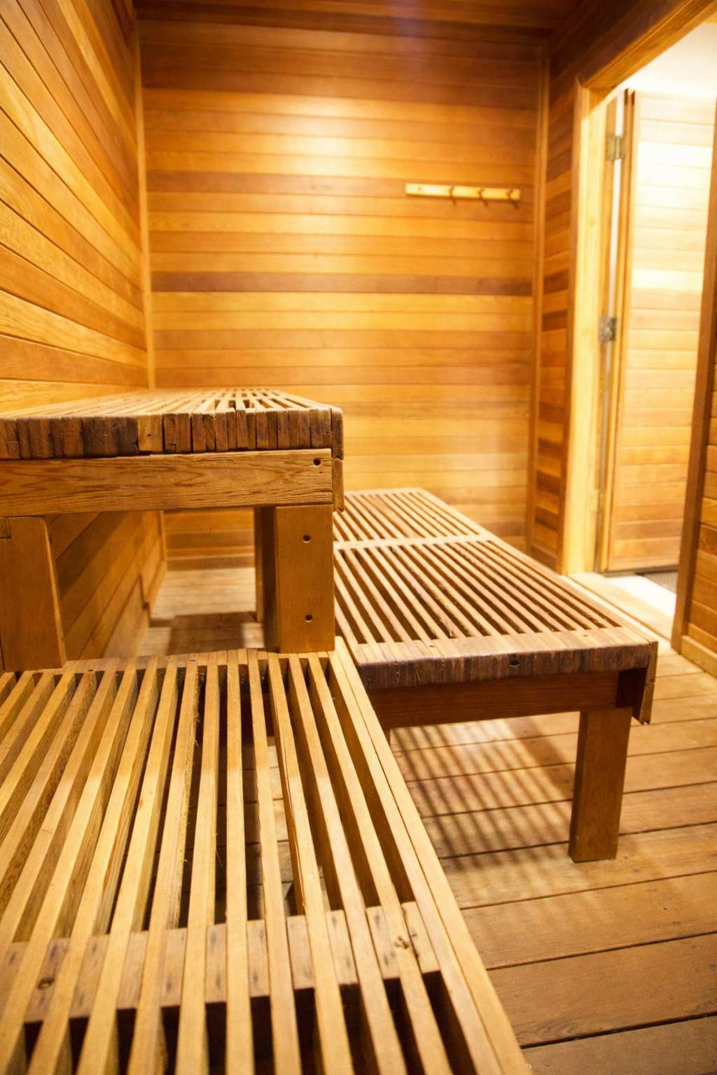 Wooden sauna with benches inside a vacation rental in Truckee. Warm lighting highlights the cozy atmosphere.