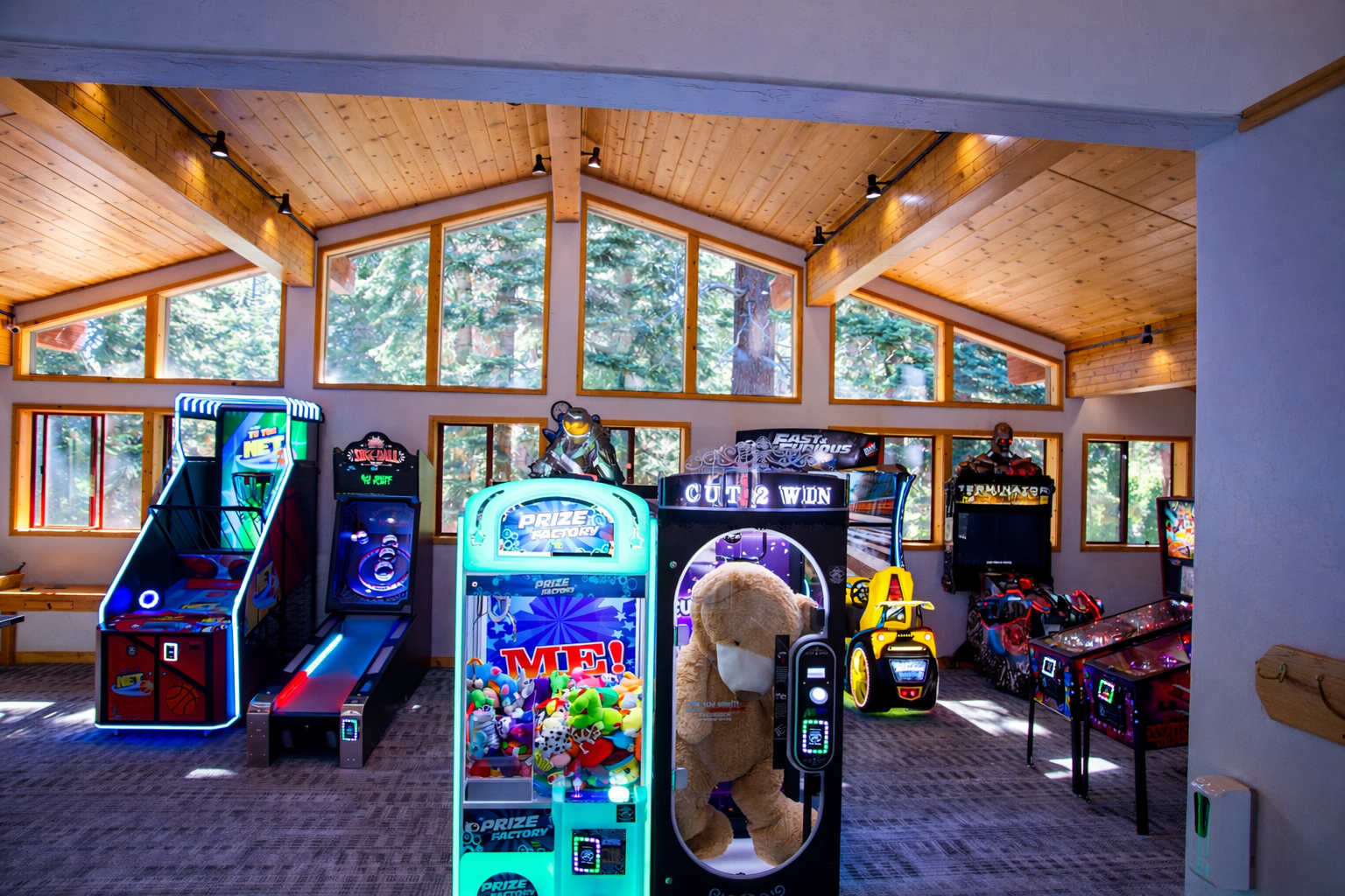 Arcade room in a Truckee vacation rental with games and large windows overlooking trees.
