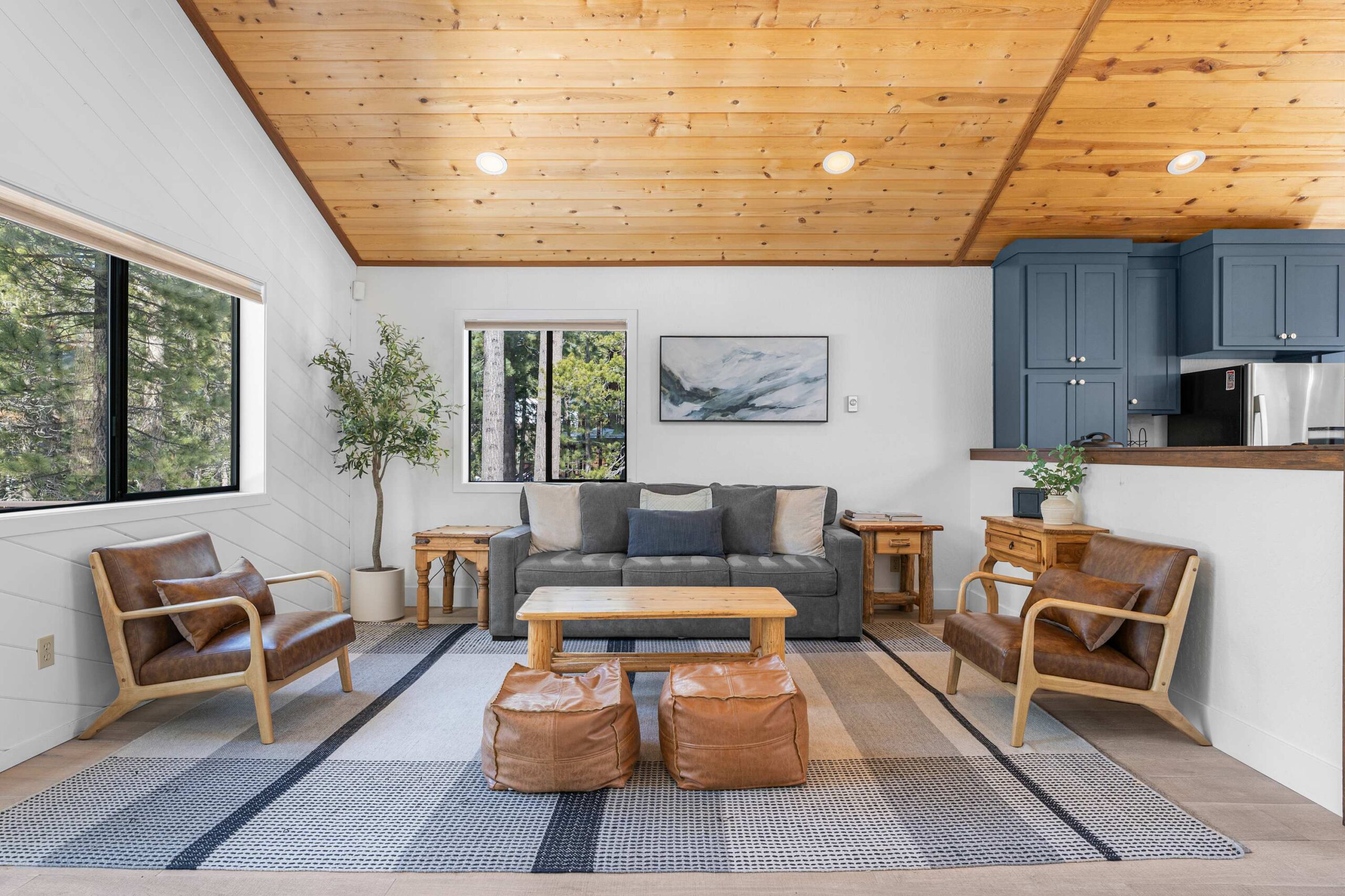 Cozy Truckee vacation rental living room with wooden ceiling, modern decor, and forest views through large windows.