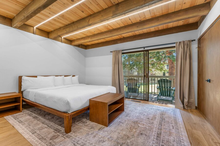 Spacious bedroom with wooden beams and sliding doors leading to a patio at a vacation rental in Kings Beach.