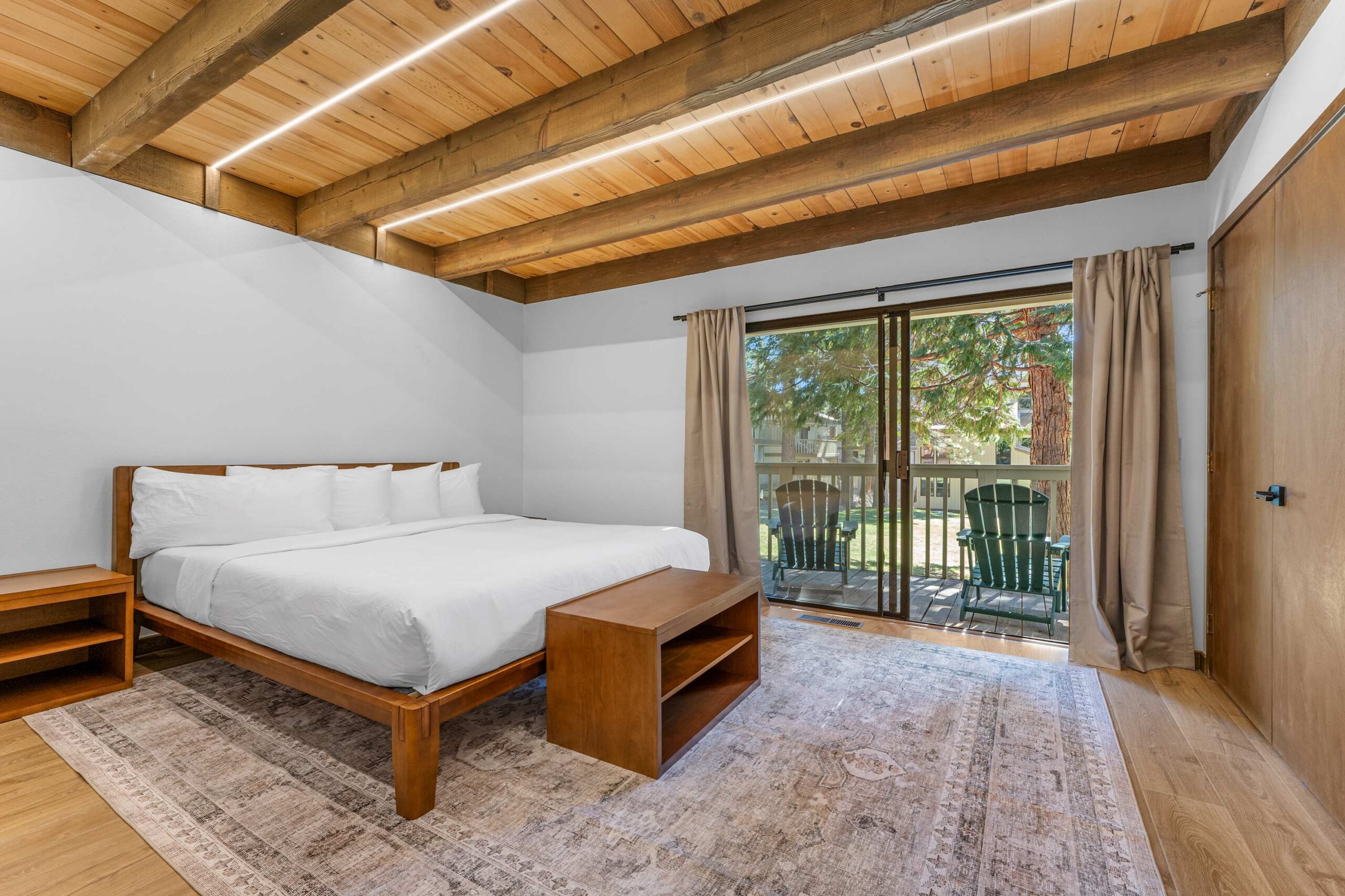 Spacious bedroom with wooden beams and sliding doors leading to a patio at a vacation rental in Kings Beach.