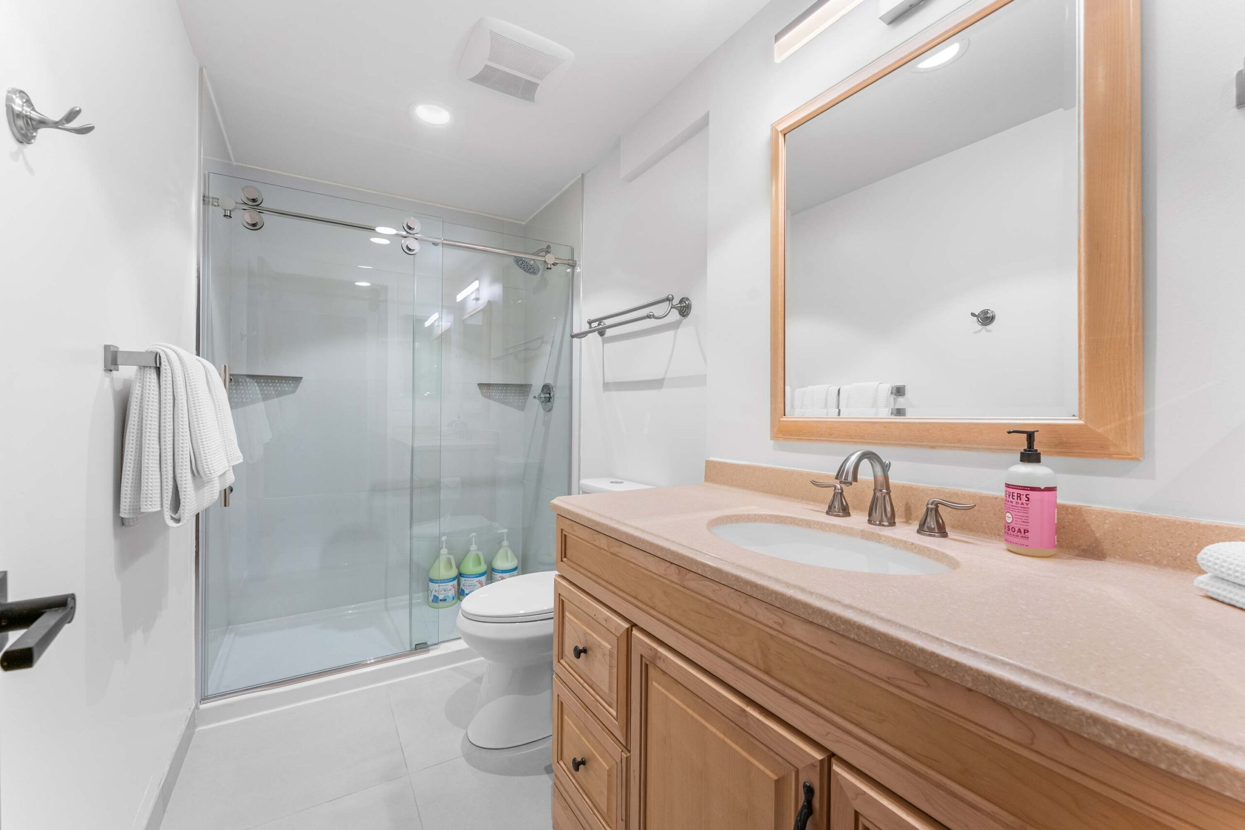 Modern bathroom in a Kings Beach vacation rental with a glass shower, wooden vanity, and large mirror.
