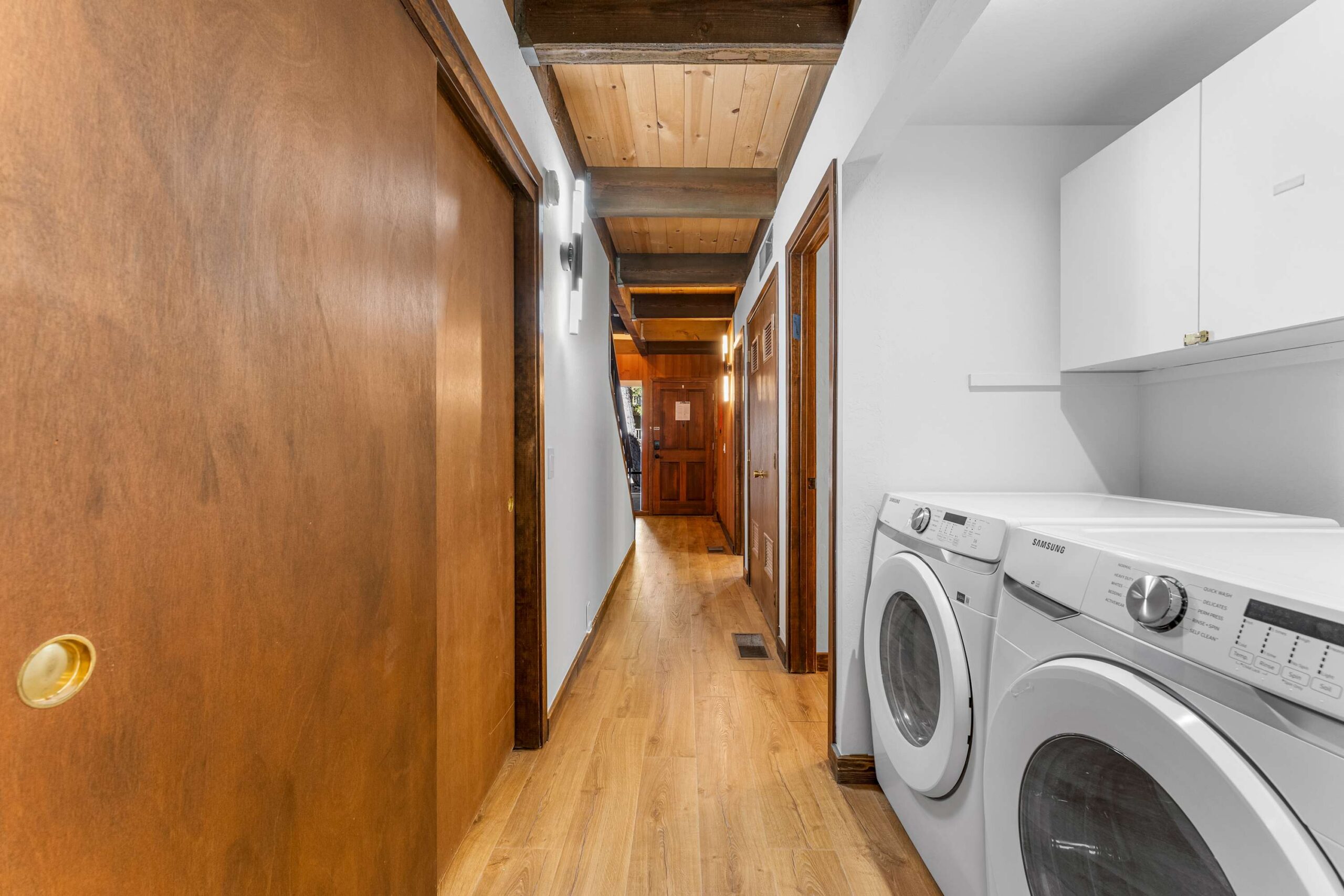 Corridor in a Kings Beach vacation rental with wood finishes and a laundry area featuring a washer and dryer.