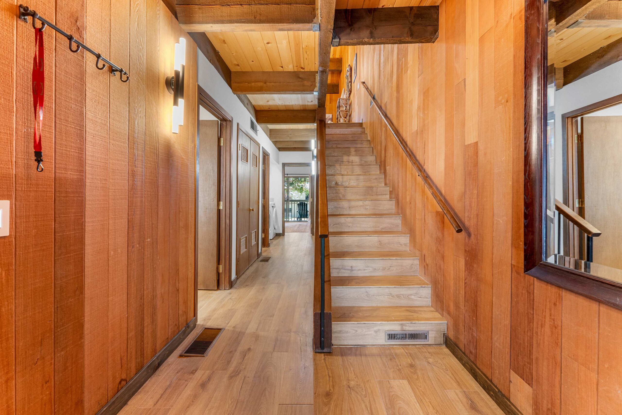 Wood-paneled interior of a Kings Beach vacation rental with staircase and hallway leading to a balcony.