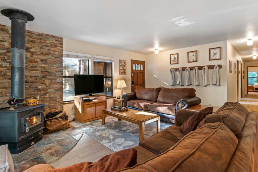 Cozy living room in a Truckee vacation rental, featuring a fireplace, sofas, TV, and wooden decor.