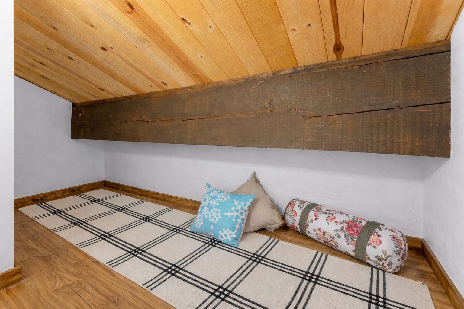 Cozy nook in a Kings Beach vacation rental, featuring a wooden ceiling, plaid rug, and decorative pillows.