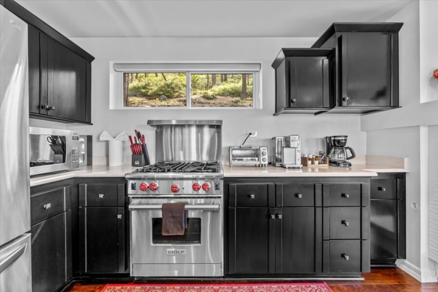 Modern kitchen in Kings Beach vacation rental with black cabinets, stainless steel appliances, and a scenic window view.