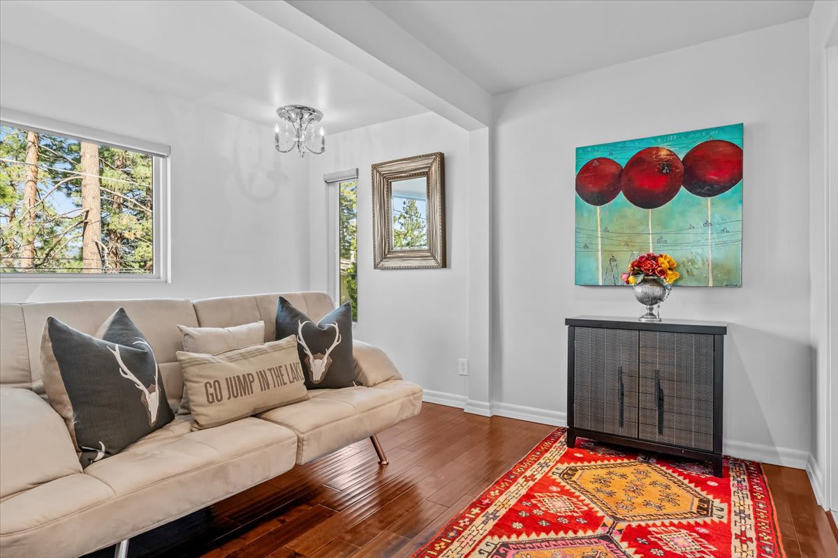 Modern living room in a Kings Beach vacation rental featuring cozy beige sofa, colorful rug, and nature view.