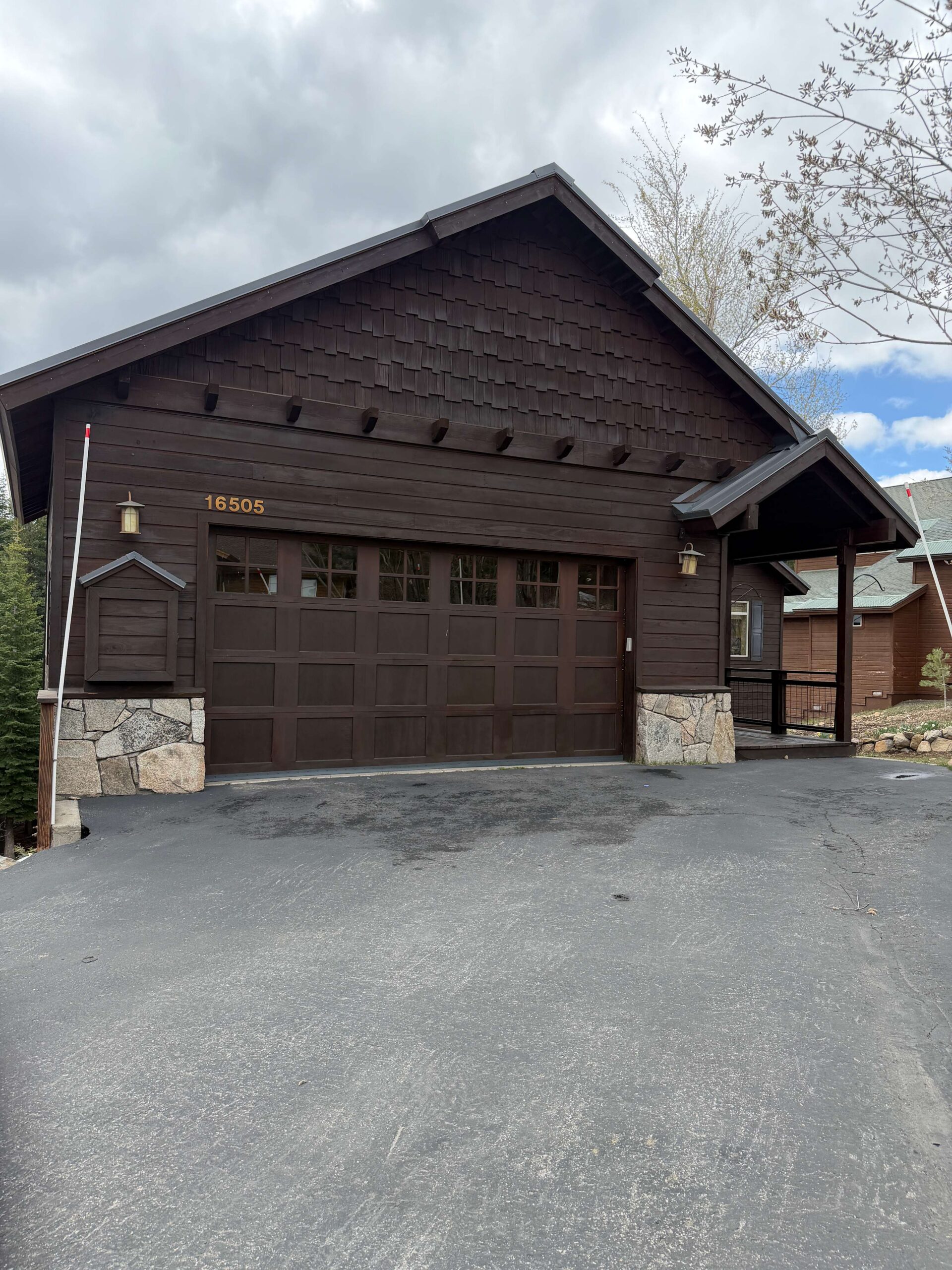Rustic brown vacation rental with stone accents in Truckee, under cloudy skies, featuring a large garage.