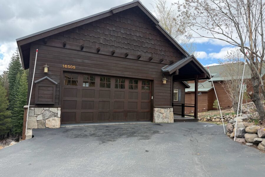 A cozy wood-front vacation rental in Truckee with a two-car garage, trees, and a clear sky in the background.