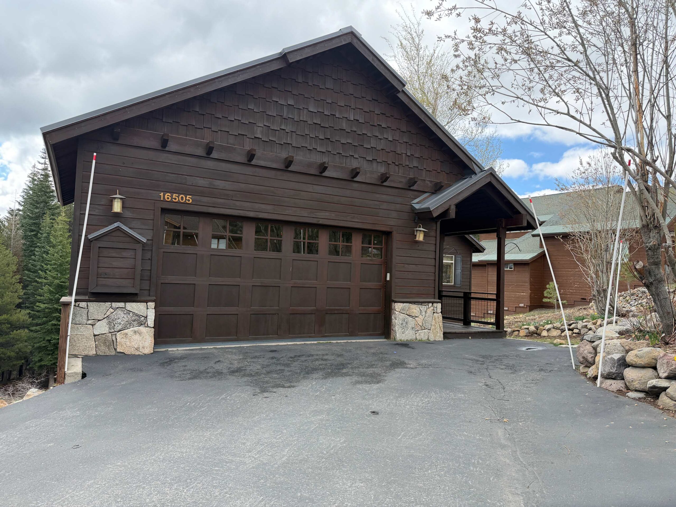 A cozy wood-front vacation rental in Truckee with a two-car garage, trees, and a clear sky in the background.