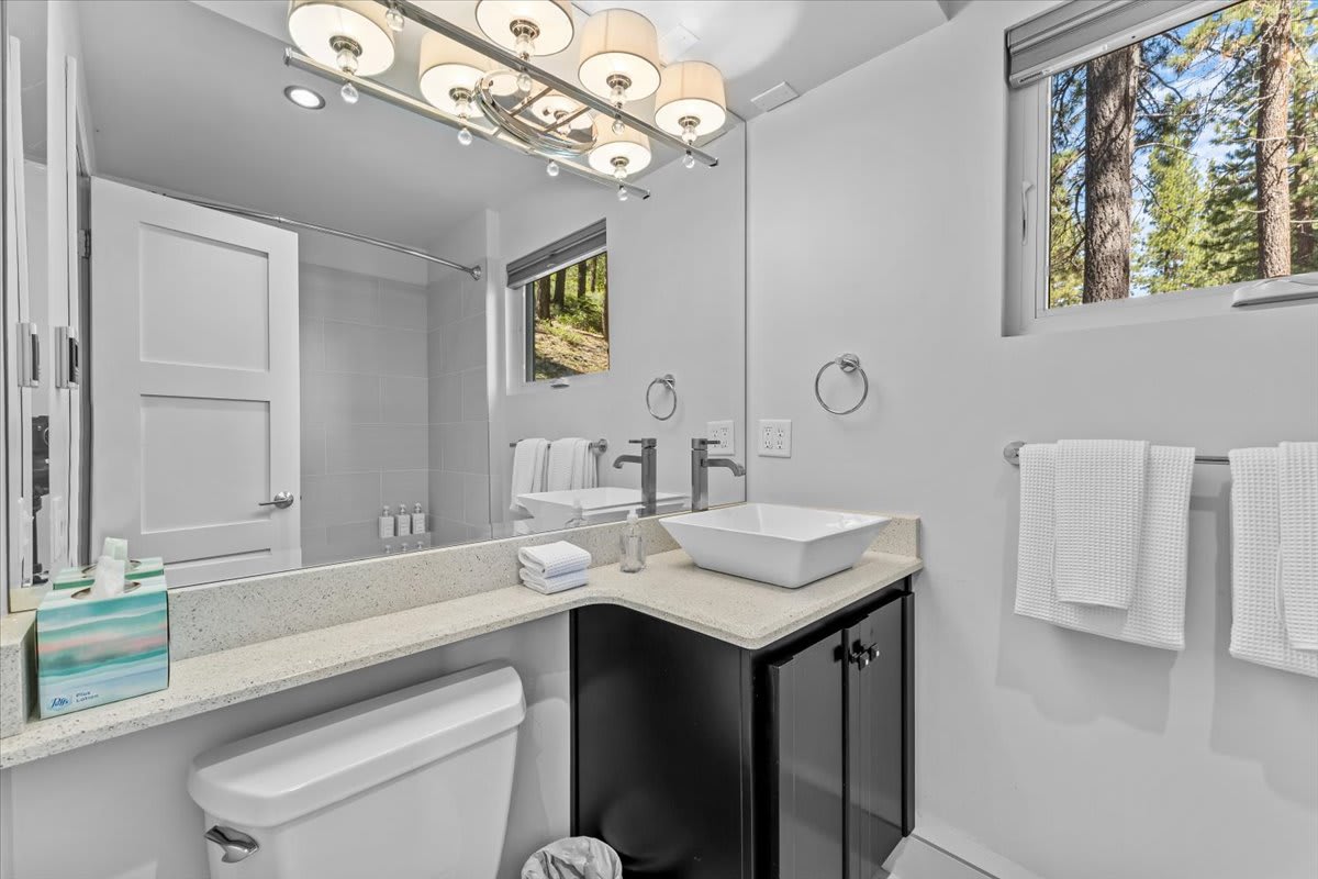 Modern bathroom in a Kings Beach vacation rental, featuring sleek fixtures, a vessel sink, and a view of the forest.