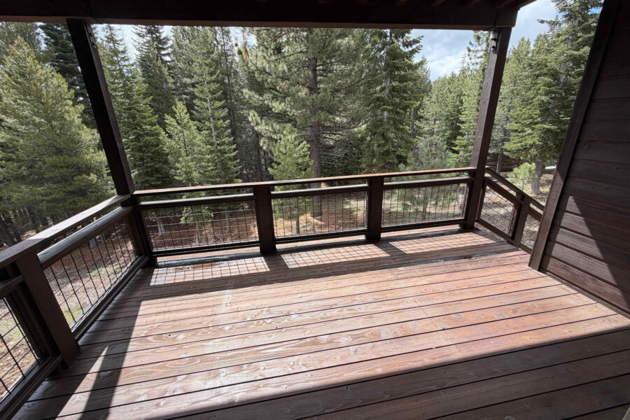 Wooden deck in a Truckee vacation rental, surrounded by lush pine trees and providing a serene forest view.