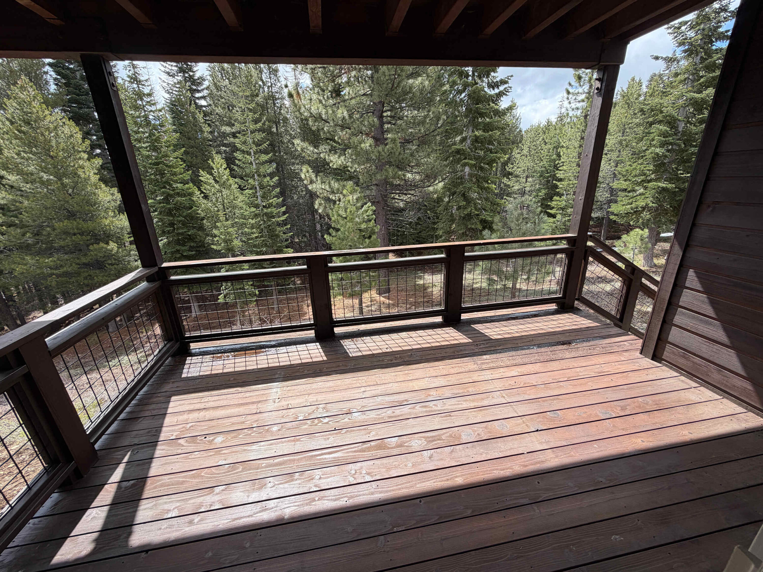 Wooden deck in a Truckee vacation rental, surrounded by lush pine trees and providing a serene forest view.
