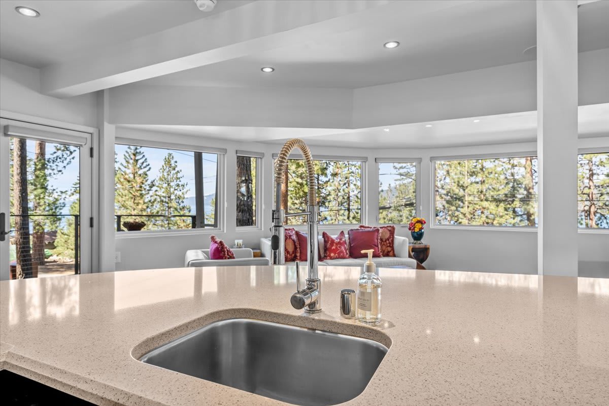 Modern kitchen in a Kings Beach vacation rental with views of trees and mountains through large windows.