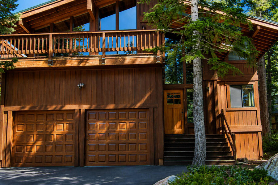 Wooden vacation rental cabin in a forested area of Carnelian Bay with a double garage and balcony.