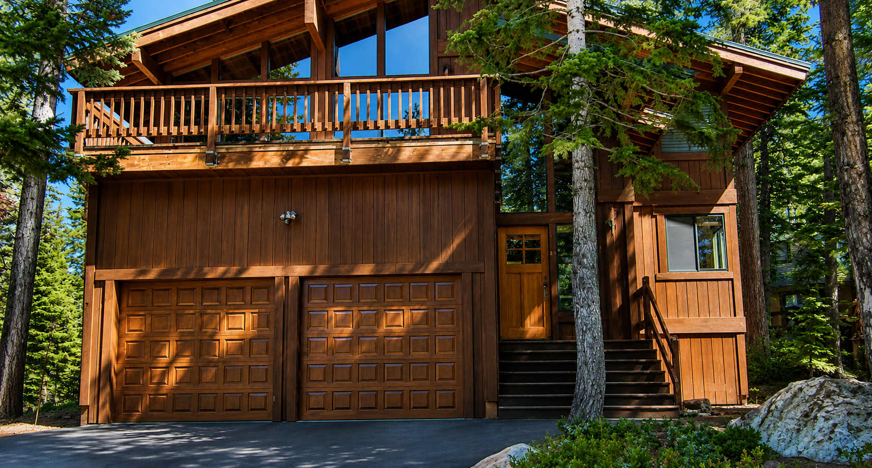 Wooden vacation rental cabin in a forested area of Carnelian Bay with a double garage and balcony.
