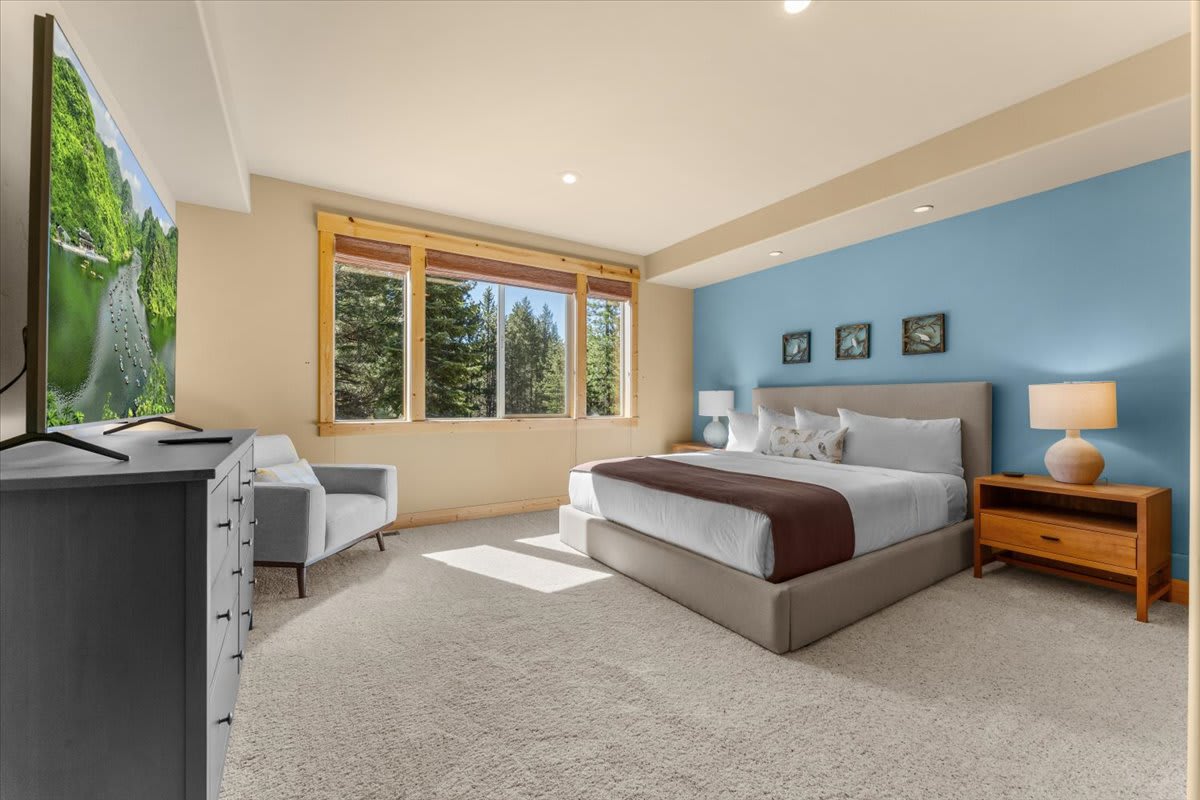 Spacious bedroom in a Truckee vacation rental with a king bed, forest view, and modern decor.