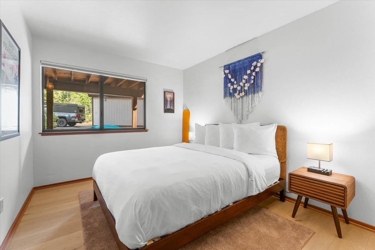 Minimalist bedroom in a Carnelian Bay vacation rental with a large window, modern decor, and a cozy wooden bed.