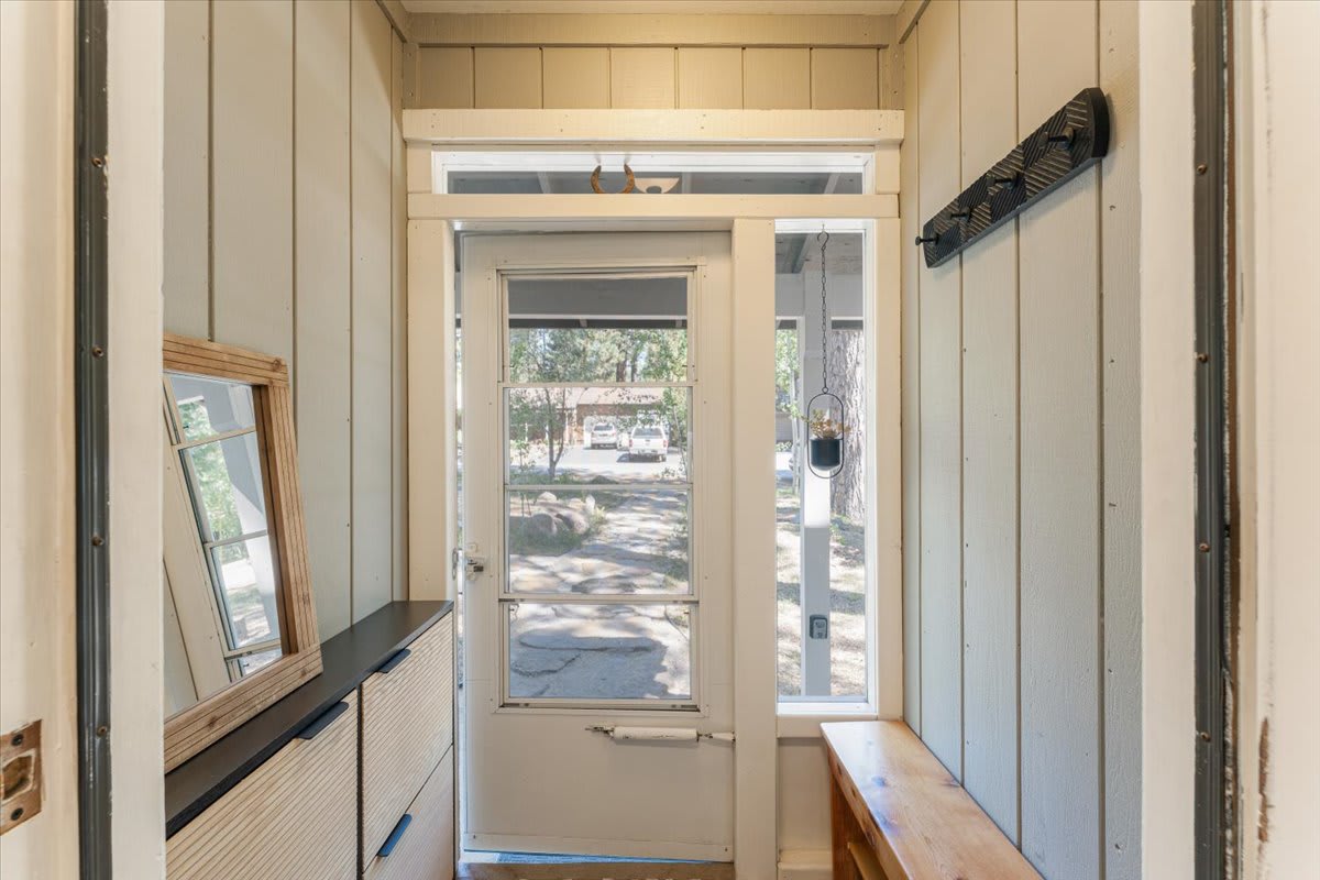 Entryway of Truckee vacation rental with natural light, wooden decor, and a view of the garden path outside.