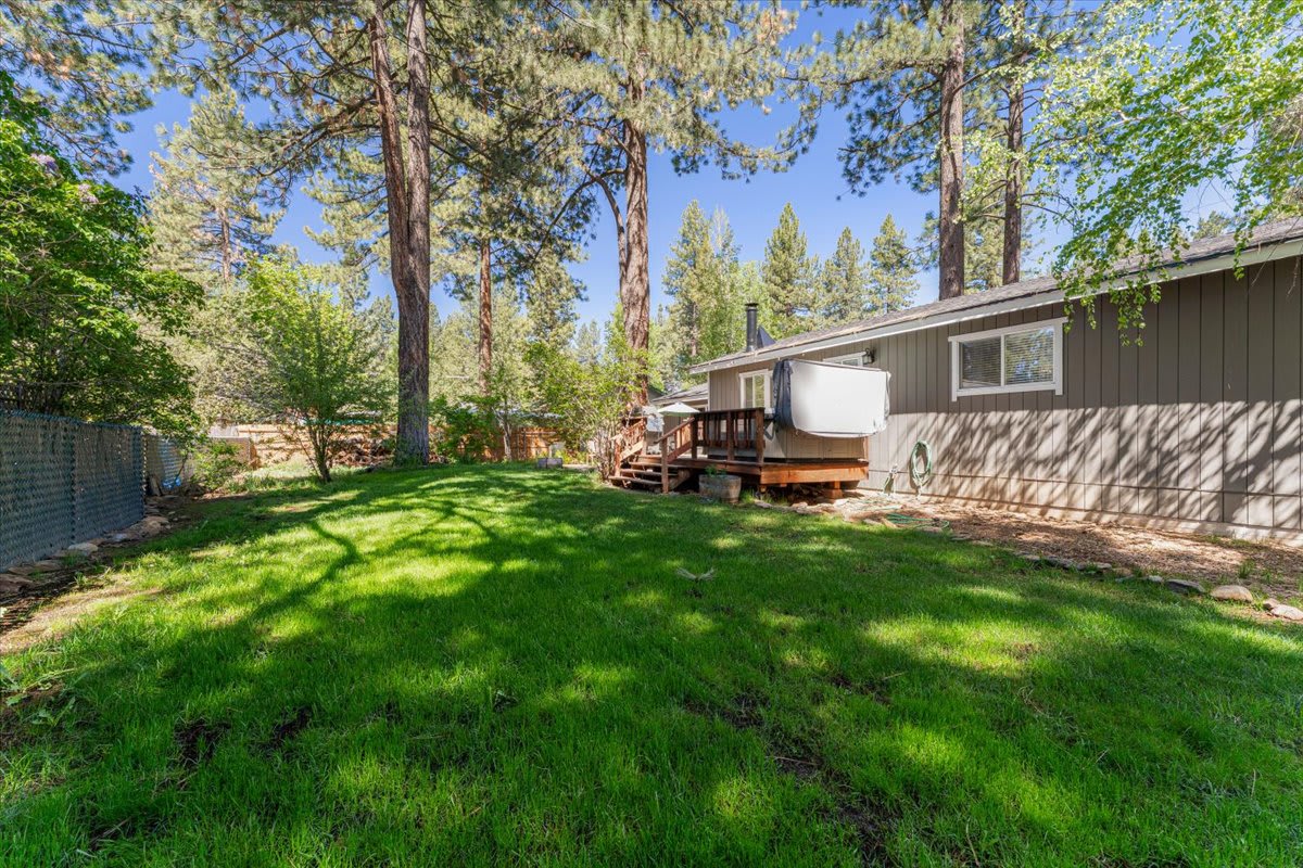 A vacation rental in Truckee featuring a lush green yard, tall trees, and a cozy wooden deck in a serene setting.
