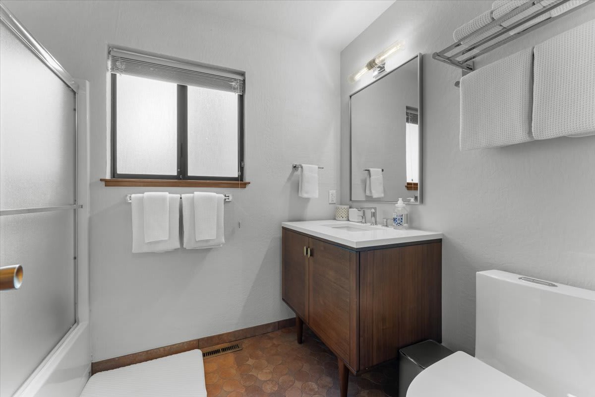 Modern bathroom in a Carnelian Bay vacation rental, featuring wooden vanity, mirror, and neatly hung white towels.