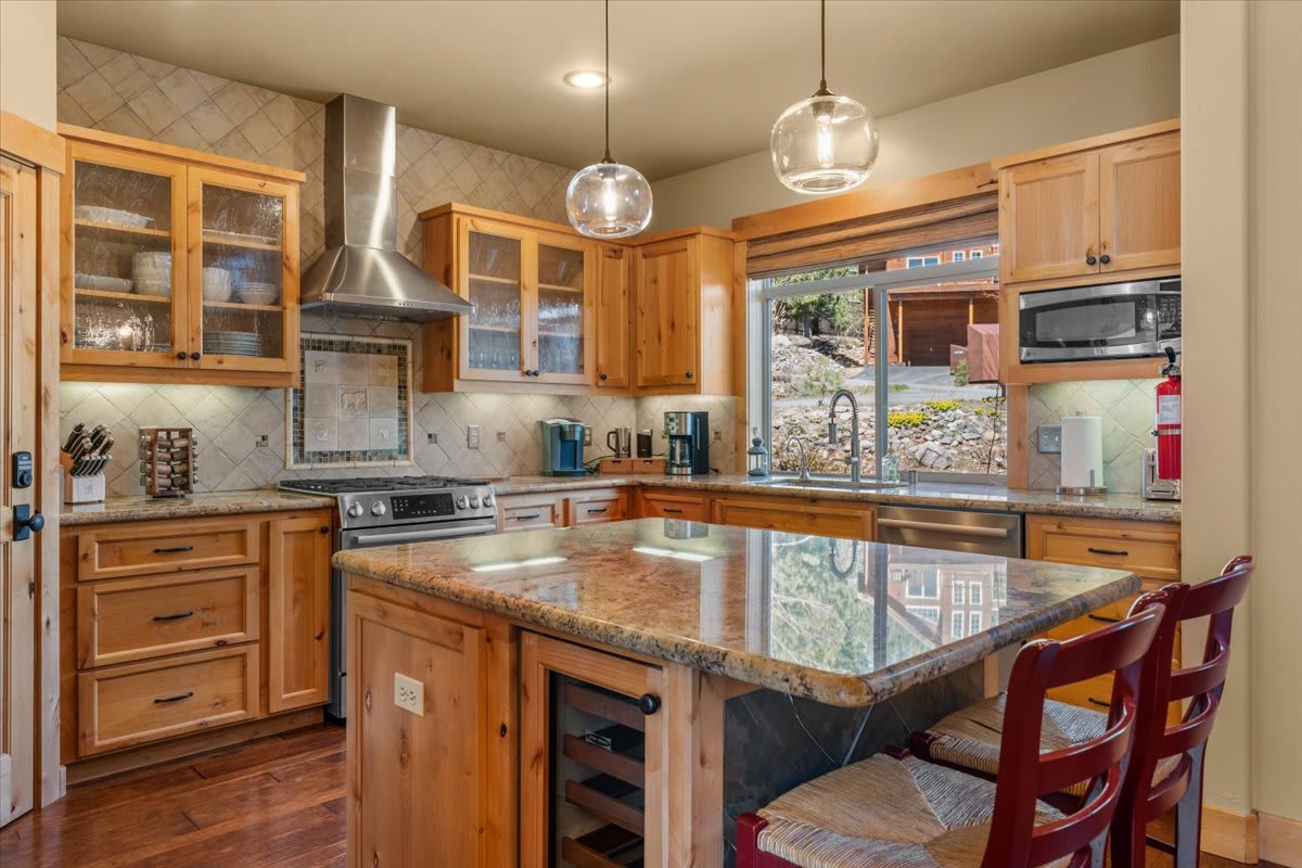 Kitchen in Truckee vacation rental with wooden cabinets, granite countertops, large window, and island seating.