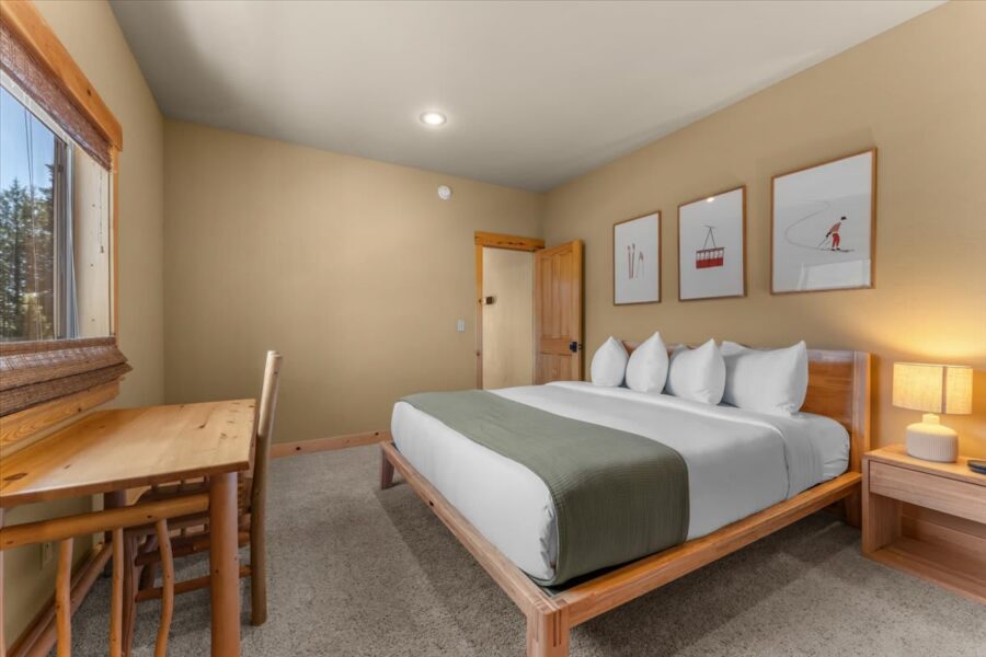 Cozy bedroom in a Truckee vacation rental with a large bed, wooden desk, and nature-themed art on the walls.
