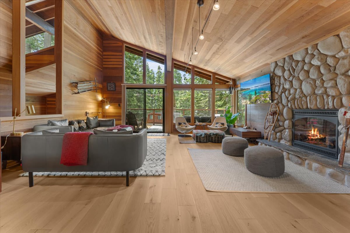 Spacious living room in a Carnelian Bay vacation rental with large windows, stone fireplace, and cozy seating.