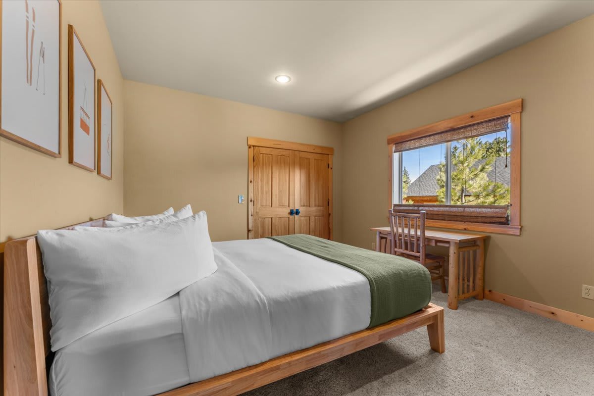 Cozy bedroom in Truckee vacation rental with wooden bed, desk, and scenic window view.
