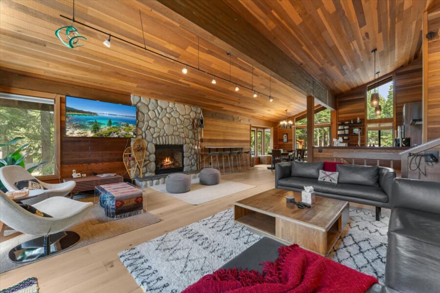 Stylish Carnelian Bay vacation rental with wood interiors, stone fireplace, cozy seating, and large windows with forest views.